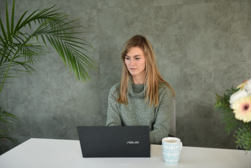 A woman sitting at a desk, focused on her laptop, exploring the concept of AI enterprise search.
